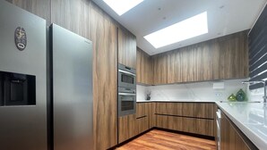 Une cuisine moderne avec des meubles en bois, des appareils électroménagers en acier inoxydable et un puits de lumière.
