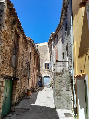 Una calle estrecha con edificios de piedra, una puerta verde y una puerta azul.