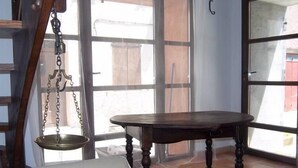 Una habitación con una mesa de madera, una balanza colgante, un sofá blanco y un tapete estampado.