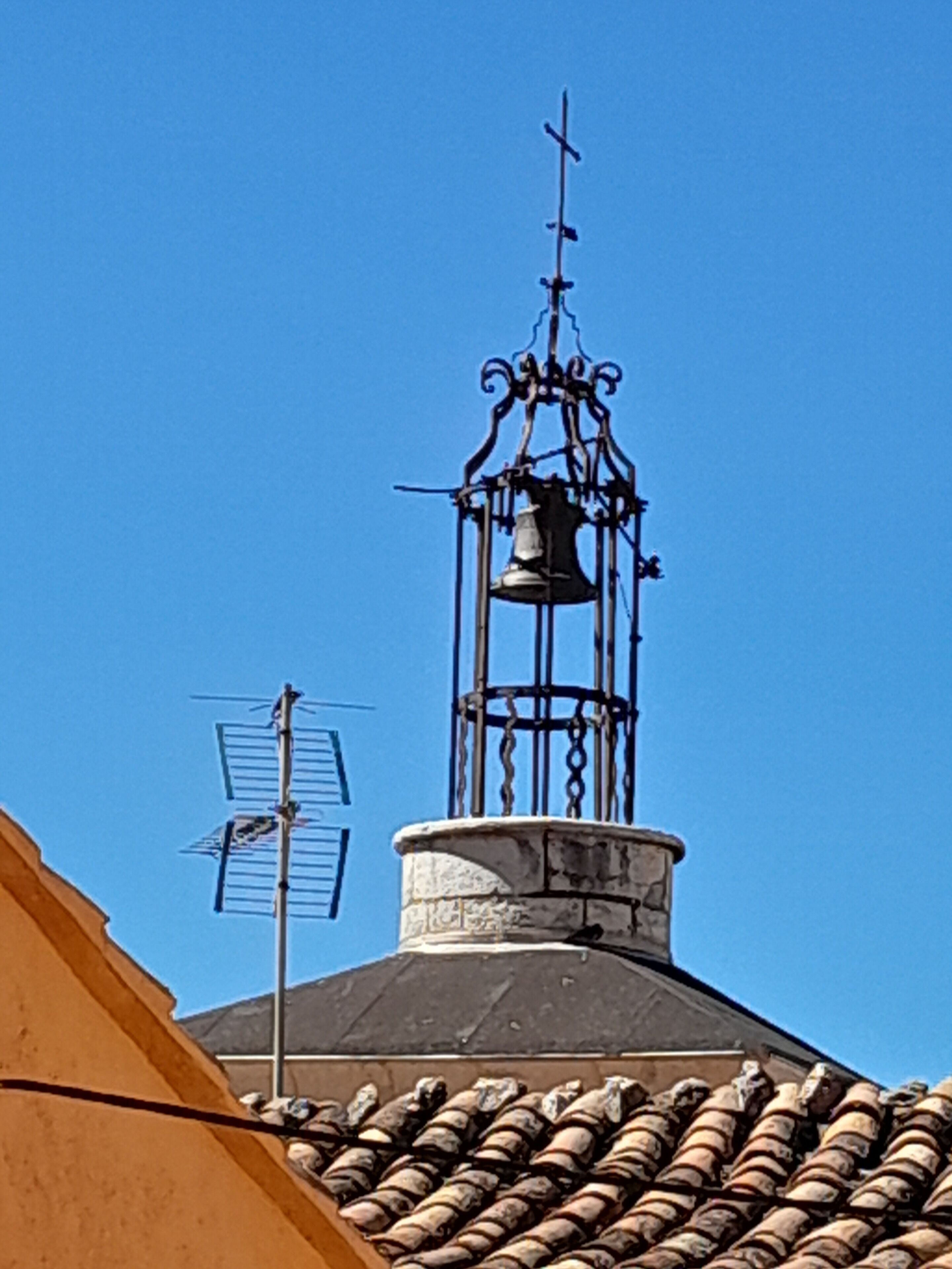 Ein Gebäude mit einem Glockenturm, einem Wetterhahn und einem Ziegeldach.