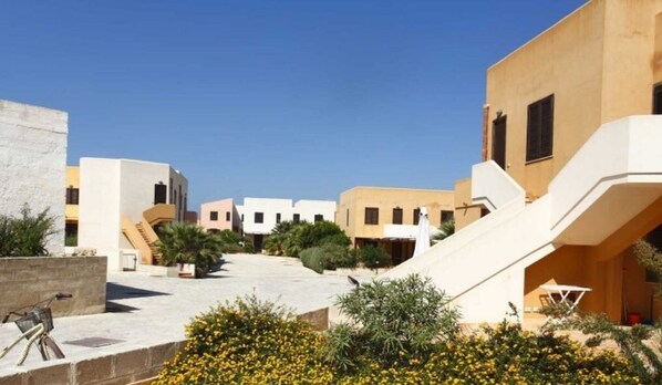 A courtyard with modern buildings, a staircase, and some greenery.