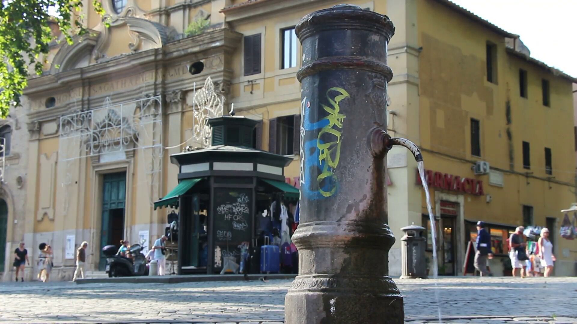 Eine Kopfsteinpflasterstraße mit einem historischen Gebäude, das aufwendige Architektur und einen Brunnen zeigt.