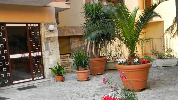 Une cour intérieure agrémentée de plantes en pot et dotée d’un sol en pierre.