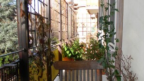 Un banc en bois dans un petit espace extérieur, agrémenté de plantes en pot et d’une porte en métal.