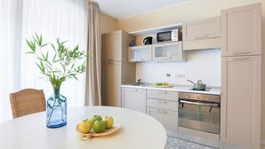 A modern kitchen with a round dining table, a vase with green leaves, and a plate of apples. - Bright and spacious, in the picturesque setting of a former cinema (Bologna)