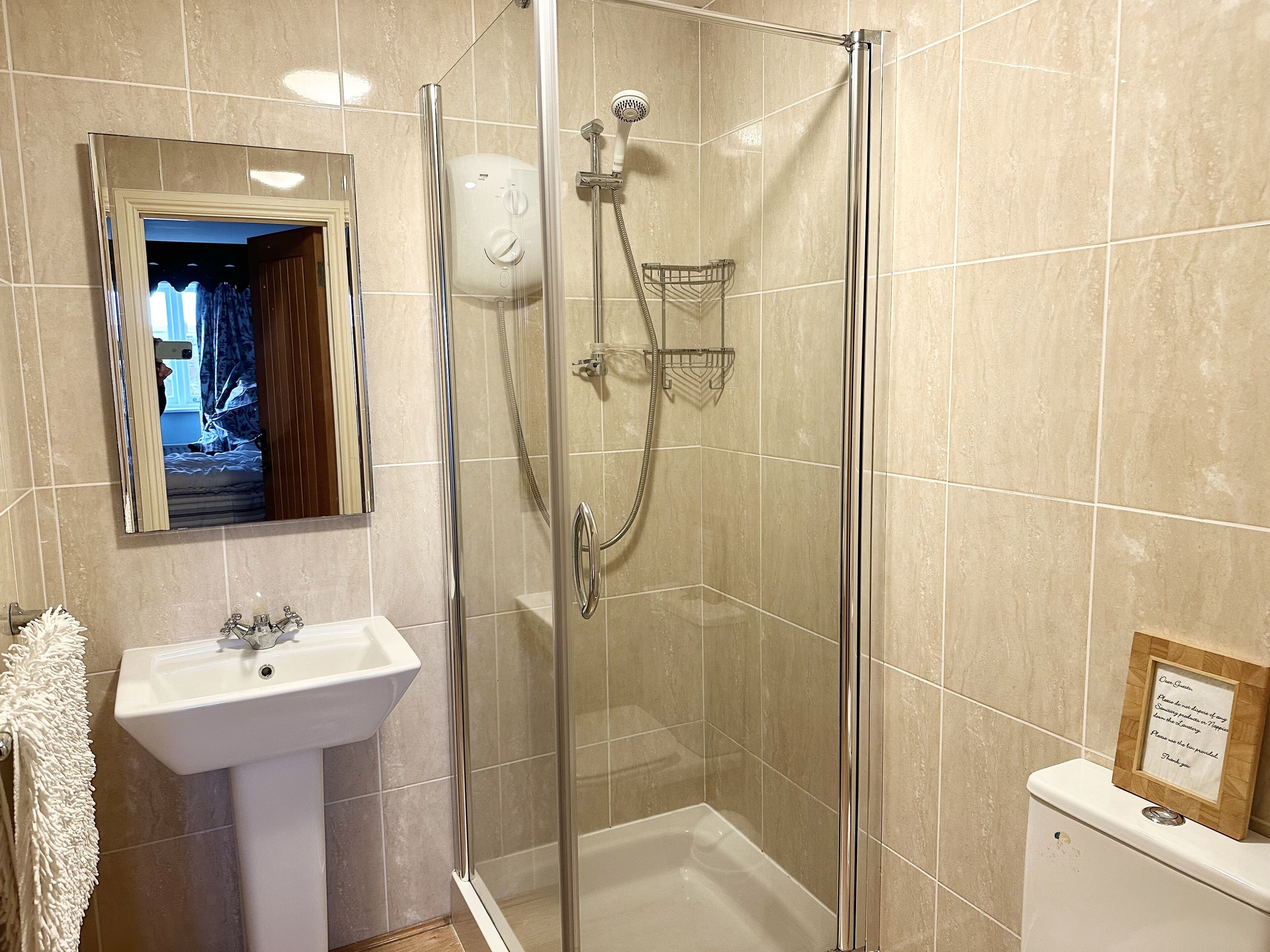 Un bany amb dutxa envidriada, un lavabo i un vàter.