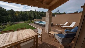 Une terrasse extérieure couverte avec un jacuzzi, des chaises longues et une table en bois.