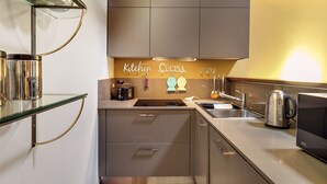 A modern kitchen with grey cabinets, a stainless steel sink, and a glass shelf.