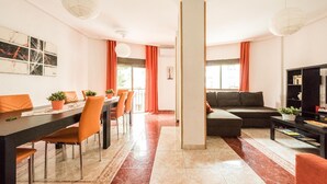 Ein modernes Wohnzimmer mit einer Couch, einem Esstisch mit Stühlen und einem Fernseher.