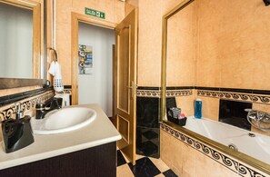 A bathroom with a sink, mirror, and toilet. There is a sign for the exit and a towel rack. - Spacious apartment with terrace. 3bed in the center (Madrid)