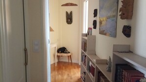 Ein Flur mit Holzboden, einer Bücherwand, einem Sessel und einem Bild an der Wand.