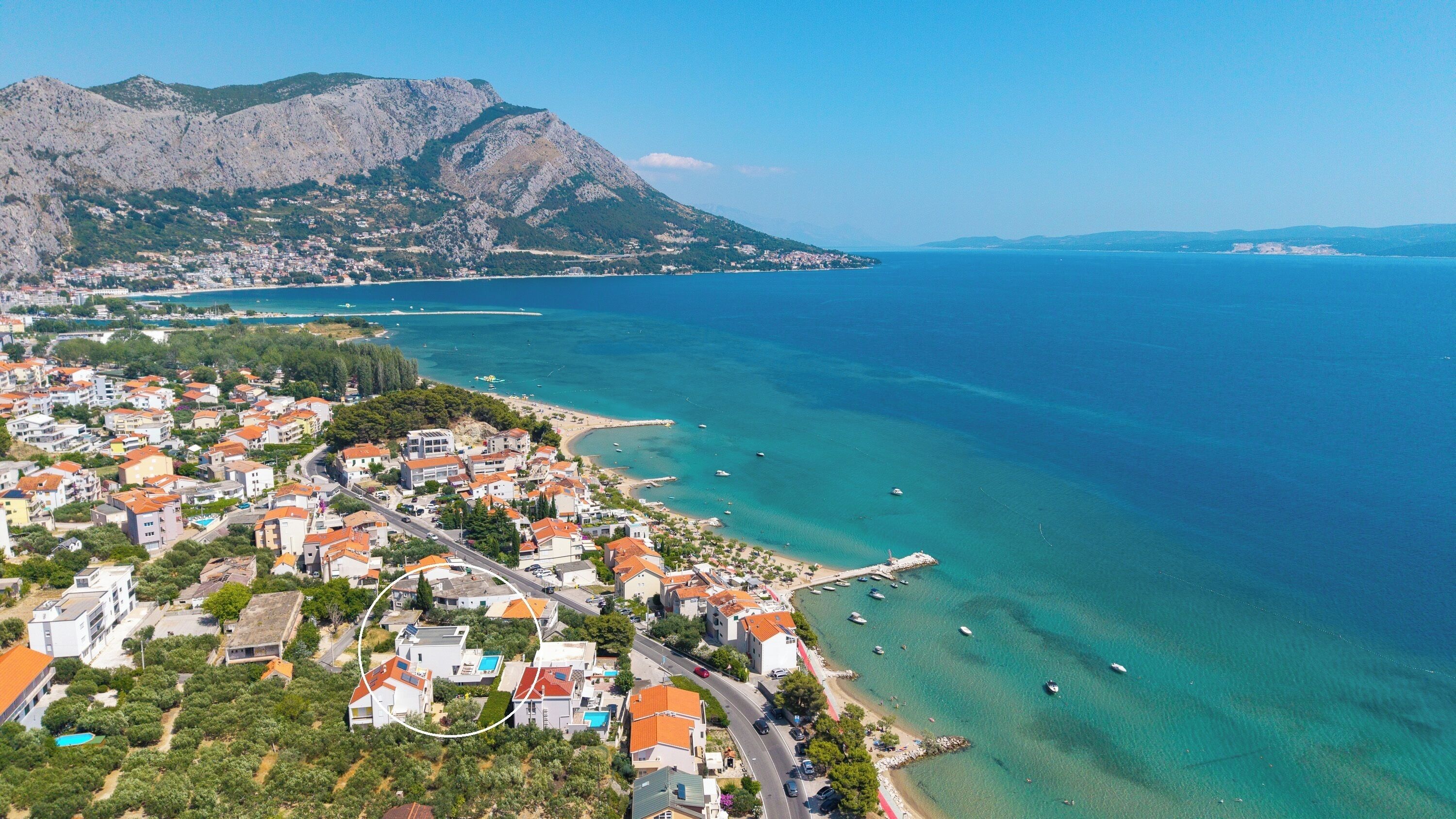 Une vue aérienne d’une ville côtière, avec des bâtiments, une plage et une montagne en arrière-plan.
