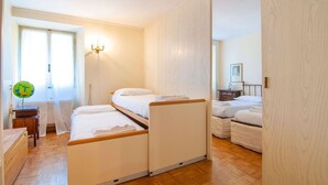 Ein Schlafzimmer mit zwei Betten, einem Nachttisch, einer Lampe und einem Fenster mit Vorhängen.