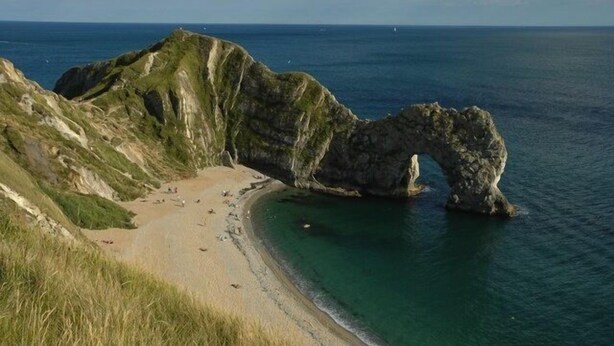 A coastal landscape with a prominent rock arch formation, a sandy beach, and clear blue waters. - 17th Century converted Coach House in Shaftesbury, Dorset (Shaftesbury)
