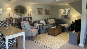 A cozy living room with a grey sofa, a wooden coffee table, and a bookshelf filled with books. - 17th Century converted Coach House in Shaftesbury, Dorset (Shaftesbury)
