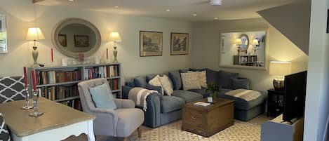 A cozy living room with a grey sofa, a wooden coffee table, and a bookshelf filled with books.