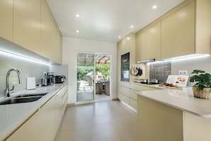 A modern kitchen with a large island, built-in appliances, and a sliding glass door leading to an outdoor area.
