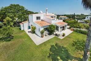 Een witte villa met pannendak, omringd door een verzorgd gazon en tuin.