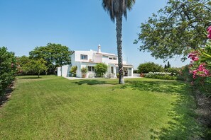 A two-story house with a well-maintained lawn and a variety of plants and trees.