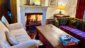 Una sala de estar acogedora con chimenea, un sofá, una mesa de centro y un tapete estampado.