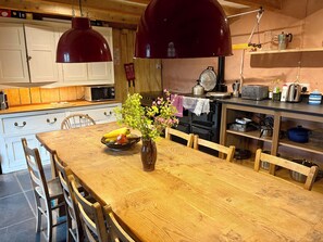 A wooden dining table with chairs, a vase with flowers, and a bowl of fruit.