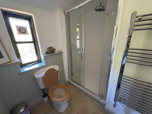 A bathroom with a toilet, a shower enclosure, and a window. - Higher Boden Barn Conversion In An Idyllic Rural Setting (Helston)