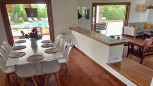 Ein Essbereich mit einem Tisch für sechs Personen, einer Küchenzeile und Blick auf Pool und Garten.