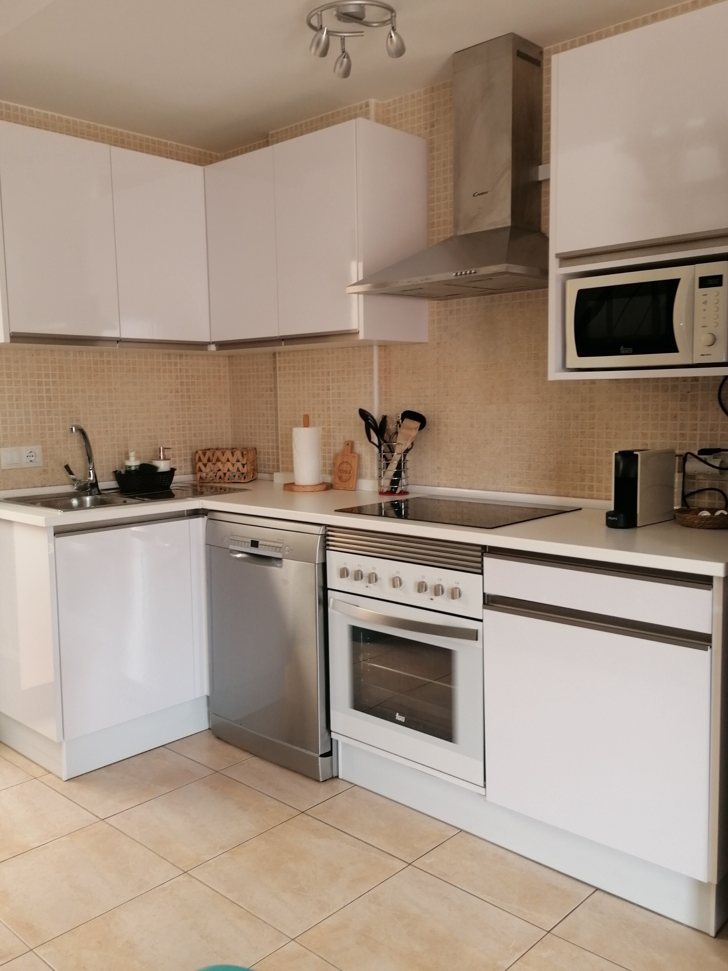 Een moderne keuken met witte kastjes, een ingebouwde magnetron, een fornuis en een vaatwasser.