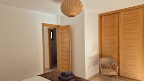 Ein Schlafzimmer mit Bett, Stuhl, Kleiderschrank und einer Pendelleuchte.