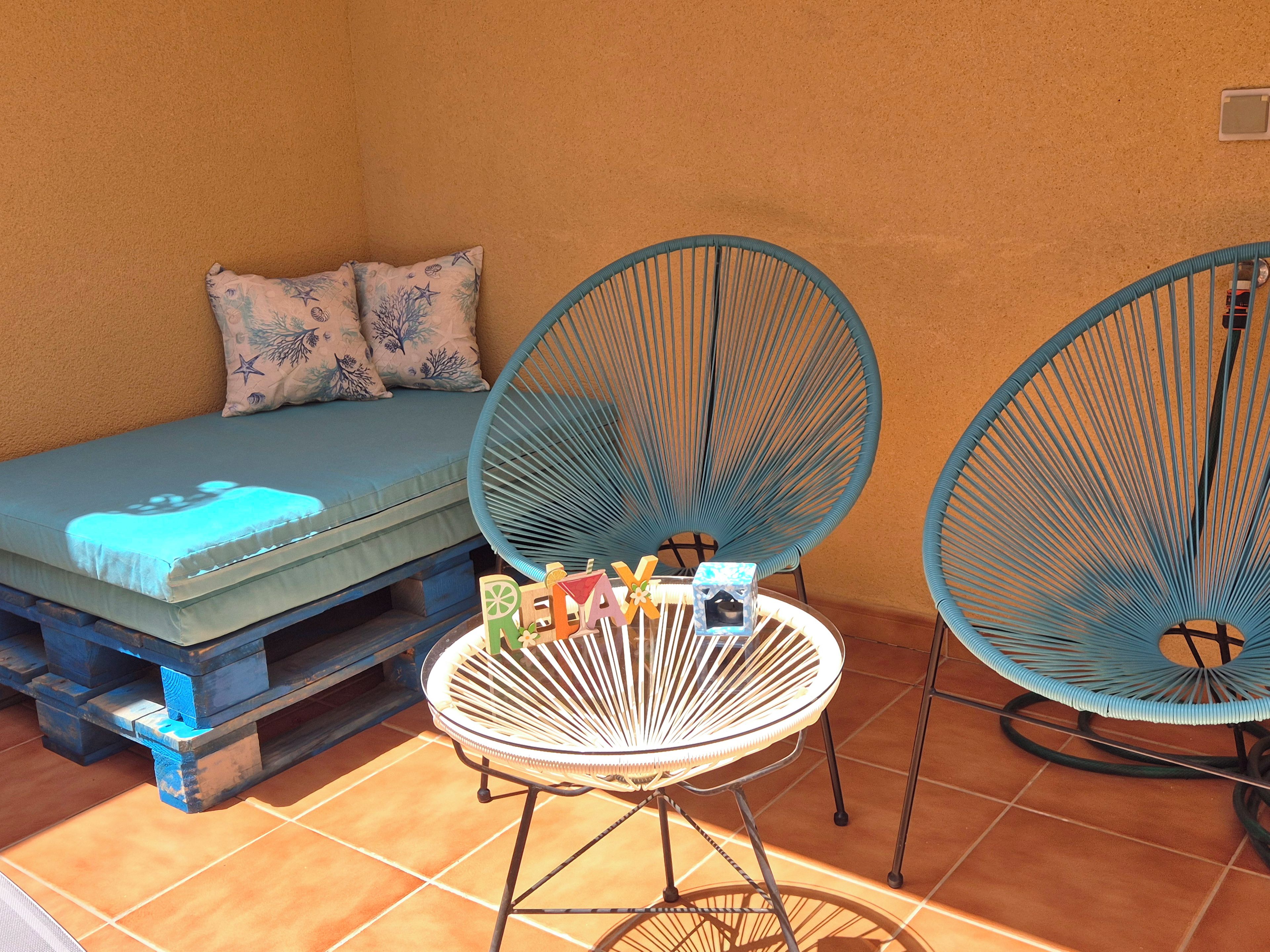 A room with a bed, two chairs, and a small table with items on it.