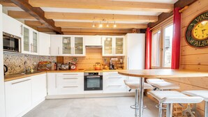 Une cuisine moderne avec des meubles blancs, un plafond en bois et un rideau rouge.
