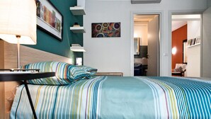 Une chambre d’hôtel avec un lit, une table de chevet, une lampe et un mur orné de tableaux.