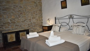 A hotel room with a stone wall, a bed with striped pillows, and a nightstand with a lamp. - Finca Carrulo with private pool for 6 people and fantastic views (Cómpeta)