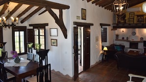 A rustic interior with a dining area, a living room, and a staircase. - Finca Carrulo with private pool for 6 people and fantastic views (Cómpeta)