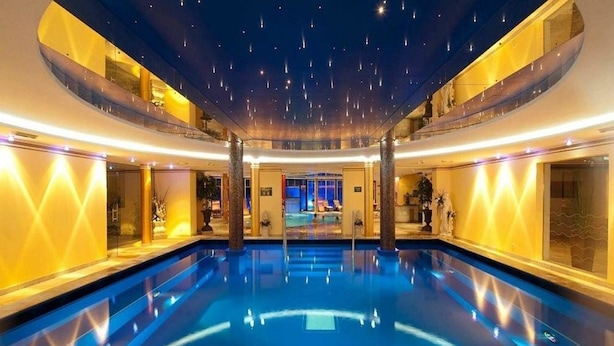 Una amplia piscina interior con efecto de techo estrellado, rodeada de paredes bien iluminadas y una zona de estar central.