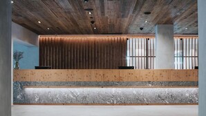 Zona de recepción con mostrador de madera, encimera de mármol y techo de listones de madera.
