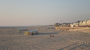 Une plage avec des gens, des tentes et des bâtiments en arrière-plan.
