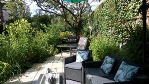 Une terrasse extérieure avec une table à manger, des chaises et un barbecue.