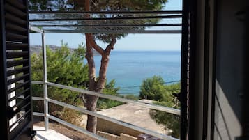 Ein Balkon mit Blick auf das Meer, einen Baum und einen klaren Himmel.