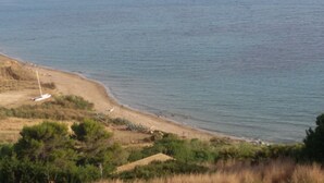 Un paysage côtier avec une plage de sable, une végétation clairsemée et un petit bateau sur le rivage.