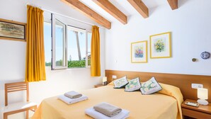 A hotel room with a bed, a chair, a nightstand, and a window with curtains. - IDEAL LARGE FAMILIES, facing the sea and a few meters from the beach of Binibeca (Binibequer)