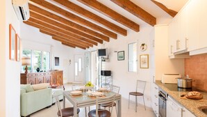A modern kitchen with wooden beams, a dining area with a glass table, and a living space with a sofa. - IDEAL LARGE FAMILIES, facing the sea and a few meters from the beach of Binibeca (Binibequer)