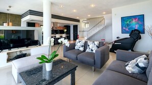 Un salon moderne avec un téléviseur à écran plat, des canapés gris, une table basse et une plante en pot.