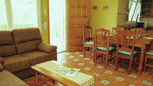 Una sala de estar con un sofá, una mesa de madera con un mantel individual y un comedor con sillas y una mesa.