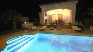 Una piscina con zona de patio, un área de estar cubierta y vistas del interior.