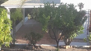Una casa con un porche cubierto, una antena parabólica y vistas del paisaje circundante.
