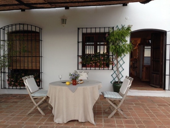 A patio with a round table and two chairs, a potted plant, and a window with a lattice design.