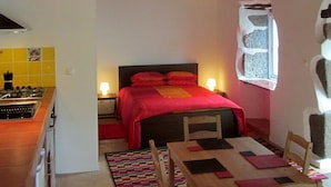 Ein gemütliches Zimmer mit Bett, Esstisch und Küchenzeile.