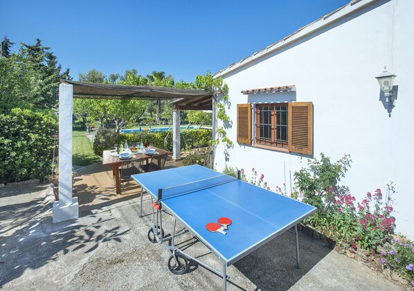 Ein Gartentisch mit Tischtennisplatte, eine Pergola, ein Esstisch und Stühle.