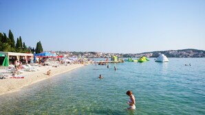 A beach with clear water, sun loungers, umbrellas, and people swimming. - Apartment in Okrug Gornji with Seaview, Terrace, Air condition, WIFI (3436-2) (Okrug Gornji)